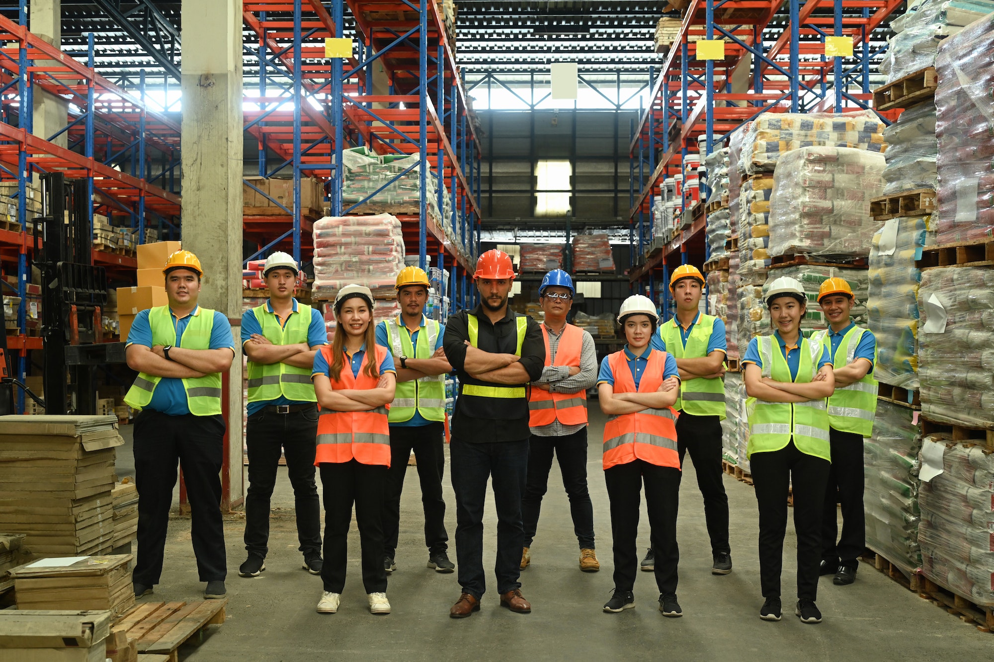 Group of warehouse worker standing in line with arms crossed together at logistic warehouse.